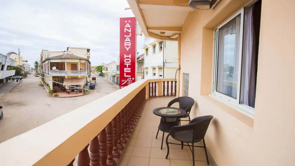 Balcon d'une chambre de Anjary Hôtel avec mobilier de terrasse et vue sur une rue de la Cité des Fleurs pour le séjour paques à mahajanga