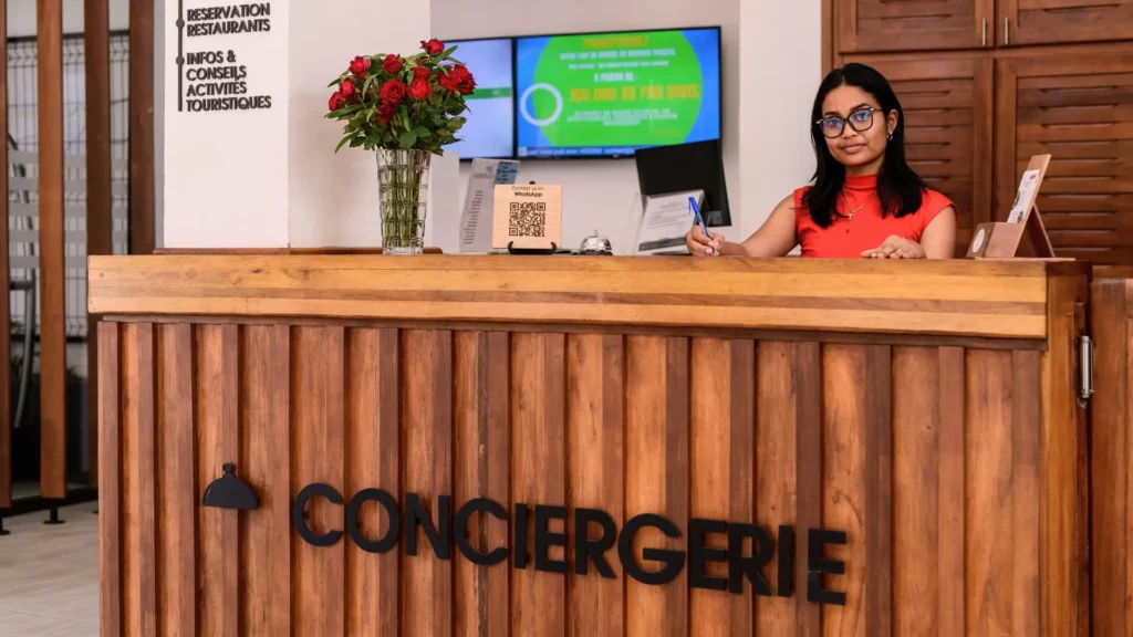 Réceptionniste souriante au comptoir de la conciergerie de Anjary Hotel 3 étoiles à Antananarivo.